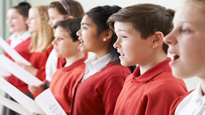 Gruppen von singenden Kindern in roten Pullis mit Notenblättern 