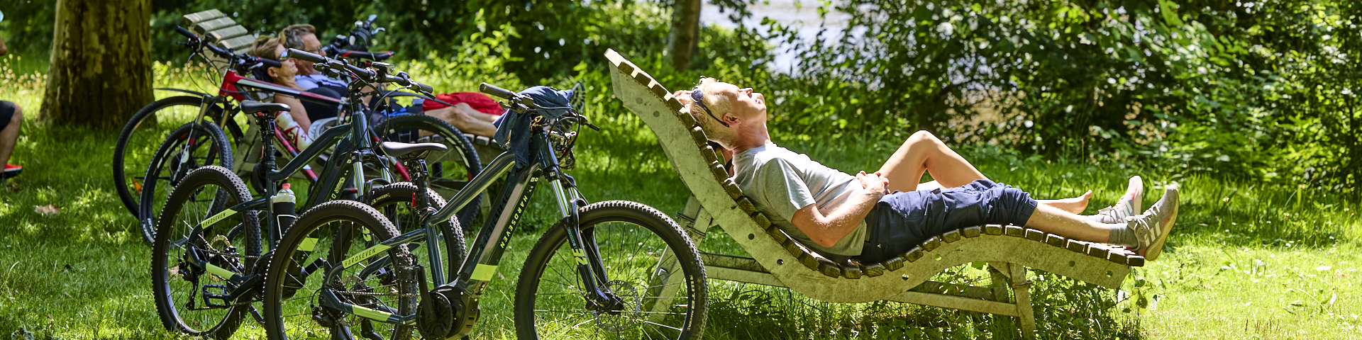Fahrradfahrer liegen im grünen auf einer Himmelsliege und sonnen sicht.
