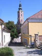 Eine Gasse in Csobánka, Ungarn. Neben einem Haus ist auch ein Kirchturm auf dem Foto zu erkennen,