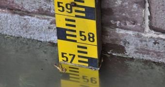 Ein gelber Pegelstandsmesser ist an einer roten Sandsteinmauer befestigt.