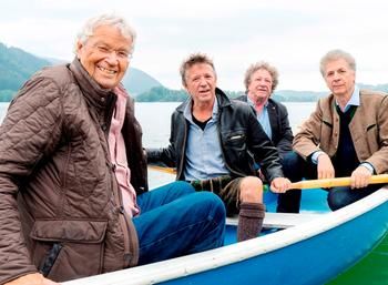 Vier Männer (Gerhard Polt und die Well-Brüder) sitzen gemeinsam im einem blauen Ruderboot.