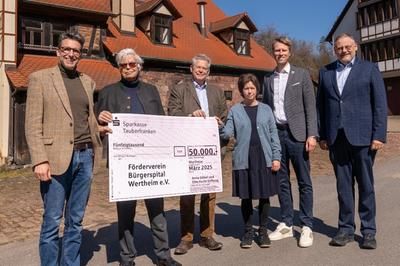 Sechs Personen zeigen einen Scheck über die Spende 50.000 Euro