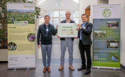 Zwei Männer übergeben einem dritten Mann das Label