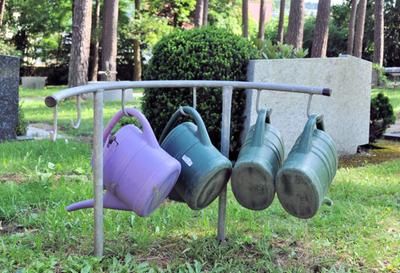 Im Vordergrund Gießkannen, im Hintergrund der Friedhof