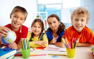 vier Kinder sitzen umgeben von Stiften und BLöcken in einer Lernumgebung