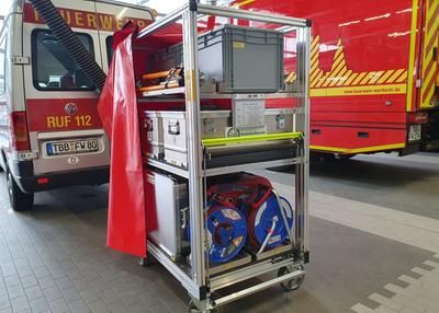 Rollwagen mit Ausrüstung vor Feuerwehrfahrzeugen