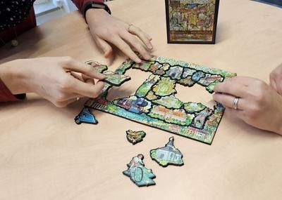 Zwei am Tisch sitzende Personen bauen ein Puzzle zusammen