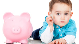 Symboldbild: Großes, rosafarbenes Sparschwein (links). Danabenein kleiner Junge mit einer Münze in der Hand. 