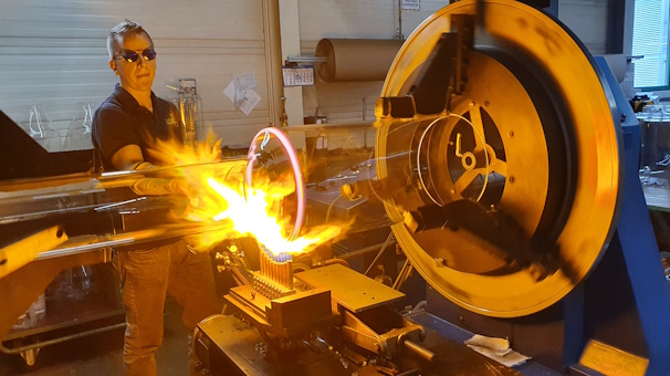 Mitarbeiter der Firma Lenz bearbeitet ein großes Laborglas mit einer Flamme