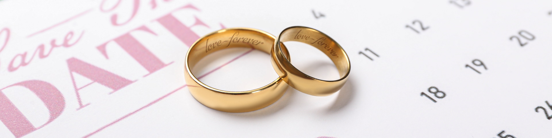 Zwei goldene Ringe liegen auf einer Save the date Karte